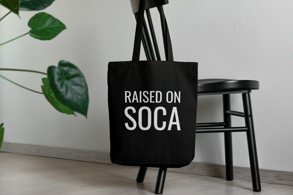 Black canvas tote bag with white Raised on Soca graphic print